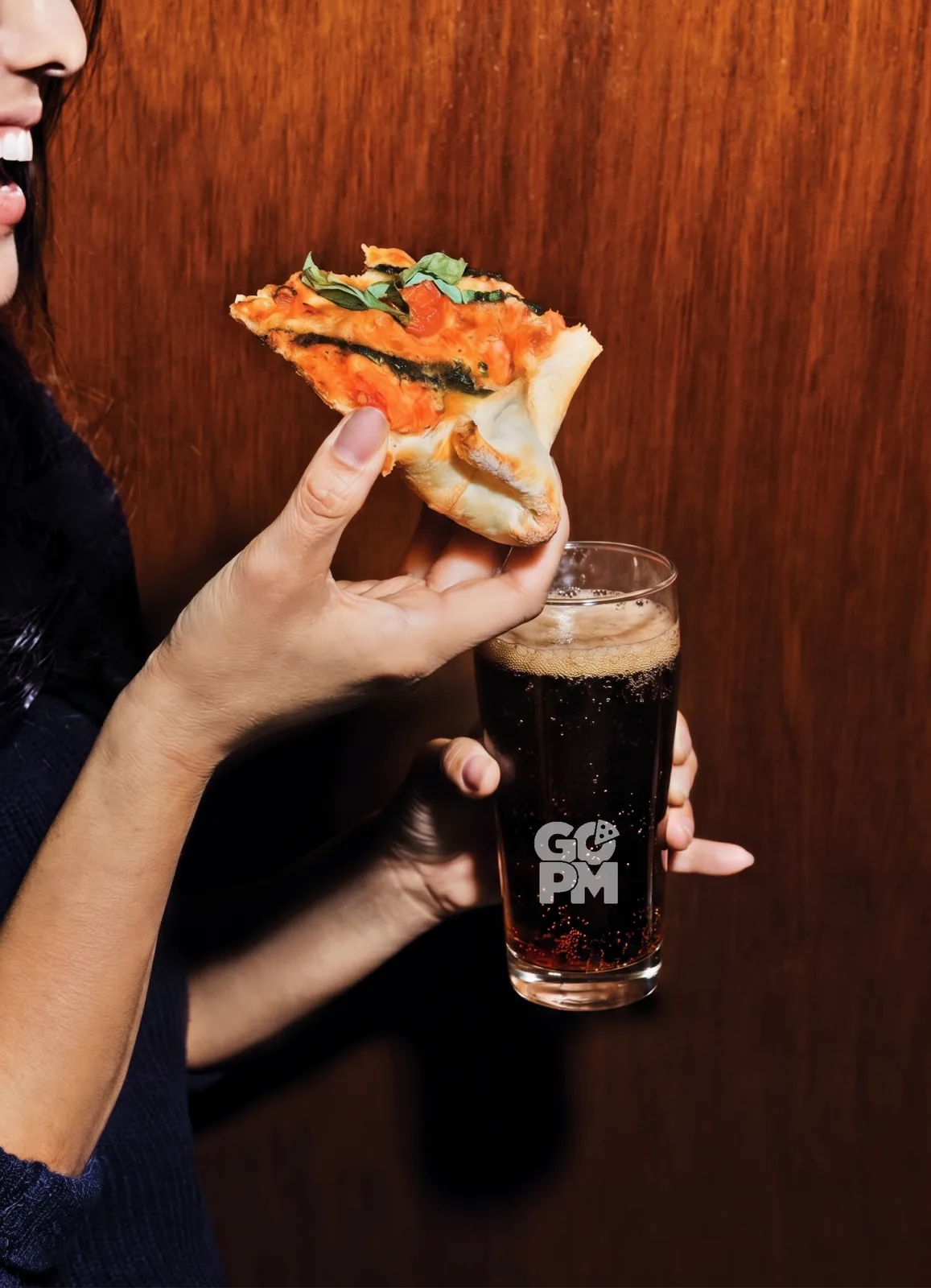 Lachende Person mit einem Stück Pizza und einem GO-PM-Glas — Platzhalter, hier kommen Fotos der beiden Gründer hin.